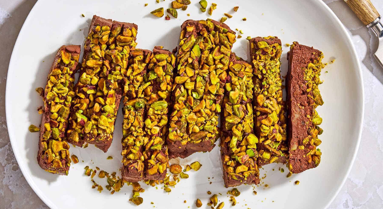 Sliced pieces of chocolate mousse topped with a generous portion of pistachios.