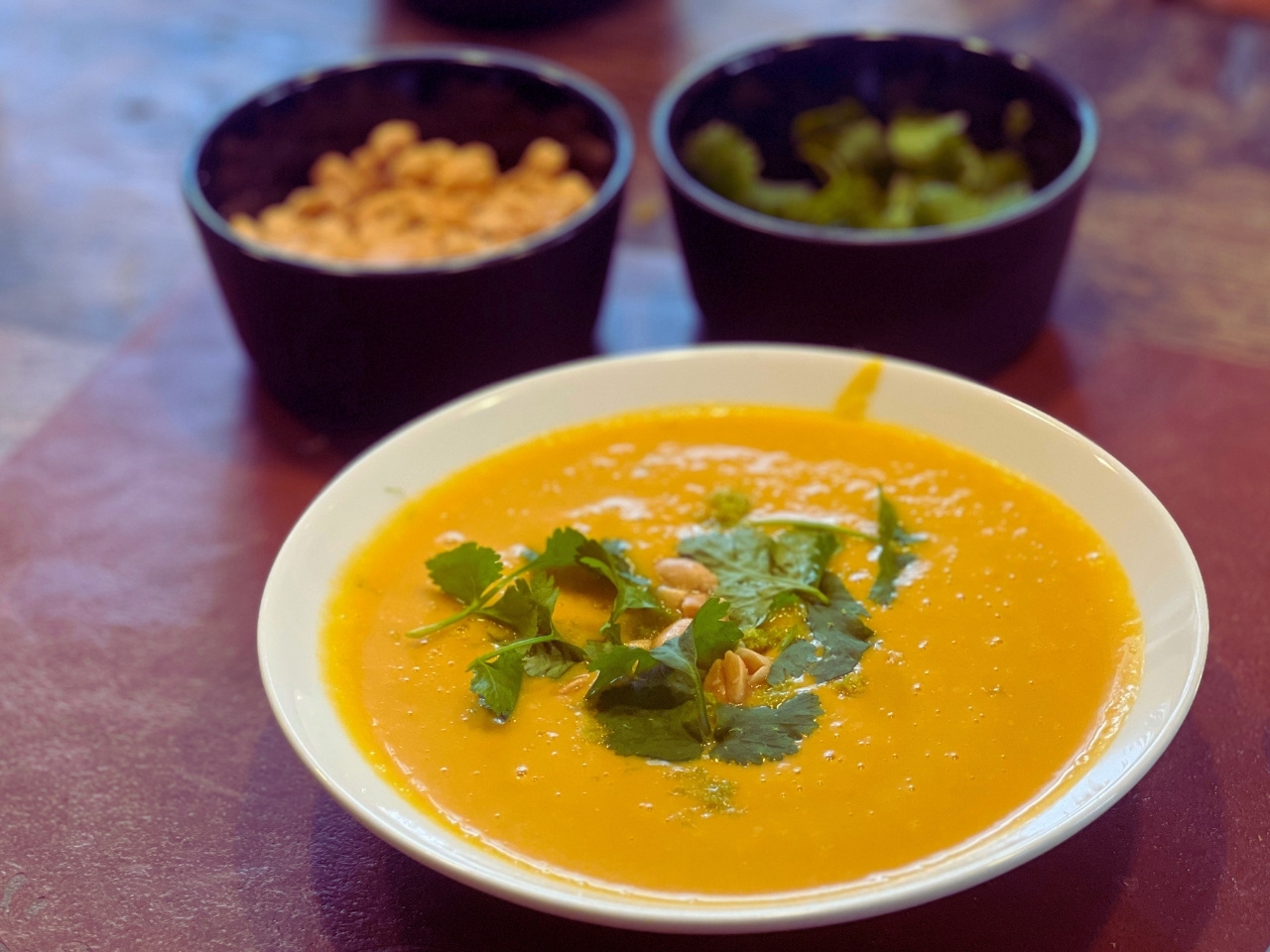 Bowl of Thai Curry Butternut Squash Soup topped with cilantro and peanuts.