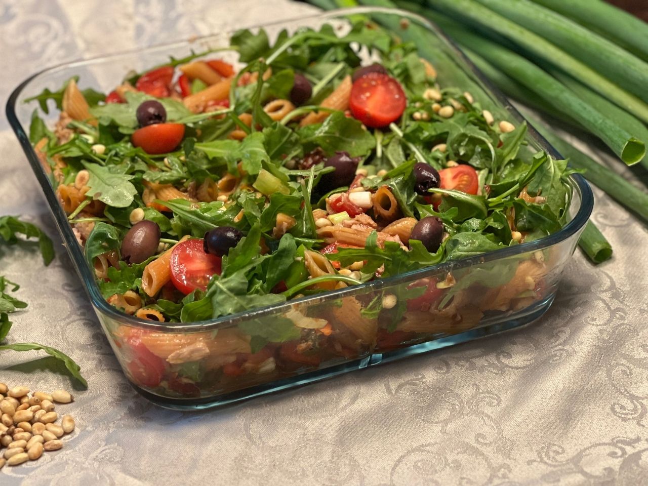 Large glass serving dish with red lentil pasta salad