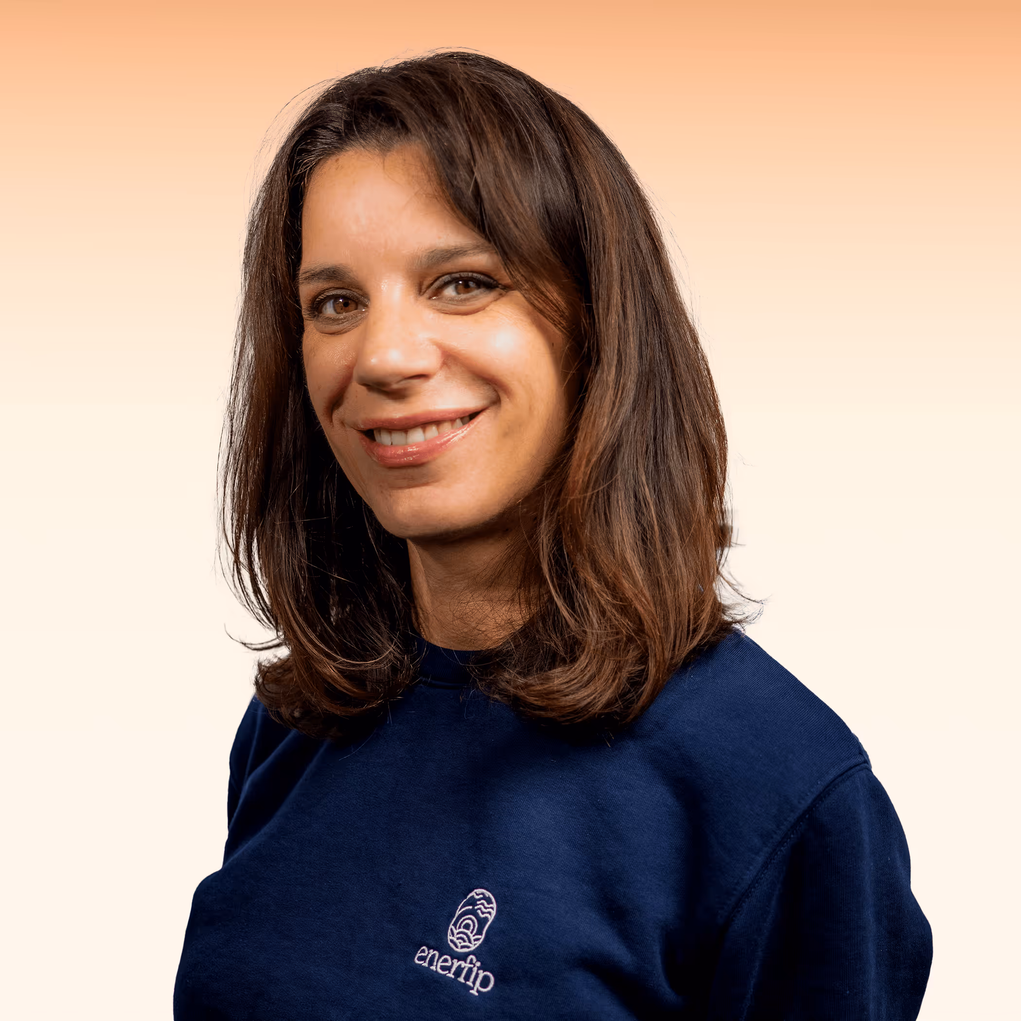 Vrouw met bruin haar draagt een donkerblauw shirt met het logo 'enerflip' tegen een lichte achtergrond.