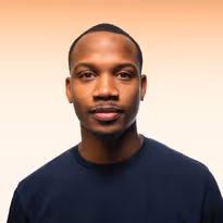 Portret van een jonge man met een donkerblauw shirt en een lichte achtergrond.