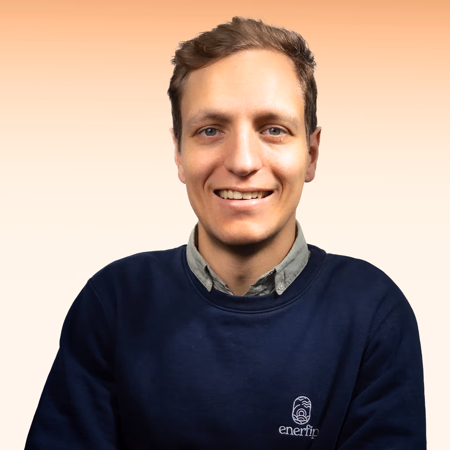 Lachende man met blauw sweater met Enerfip-logo op een beige achtergrond.