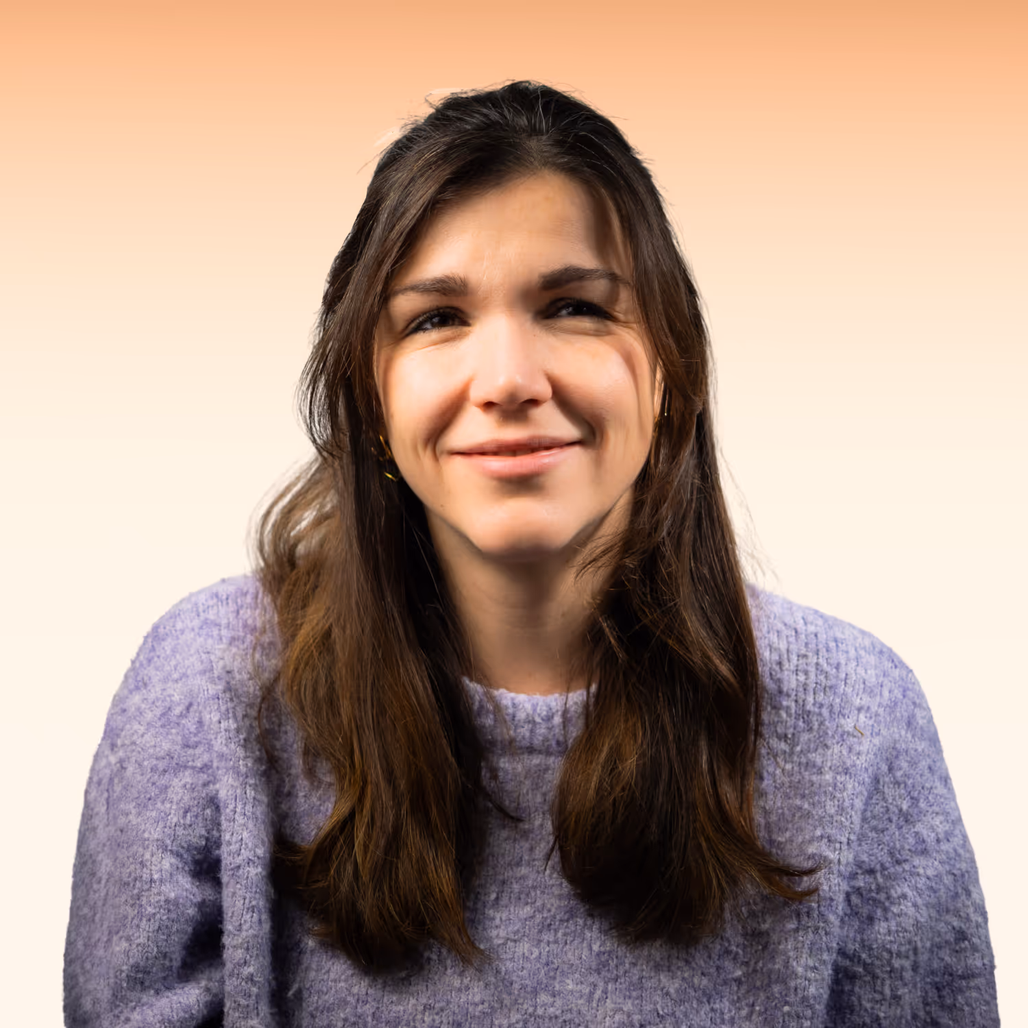 Vrouw met lang bruin haar die een paarse trui draagt, glimlacht tegen een zachte gele achtergrond.