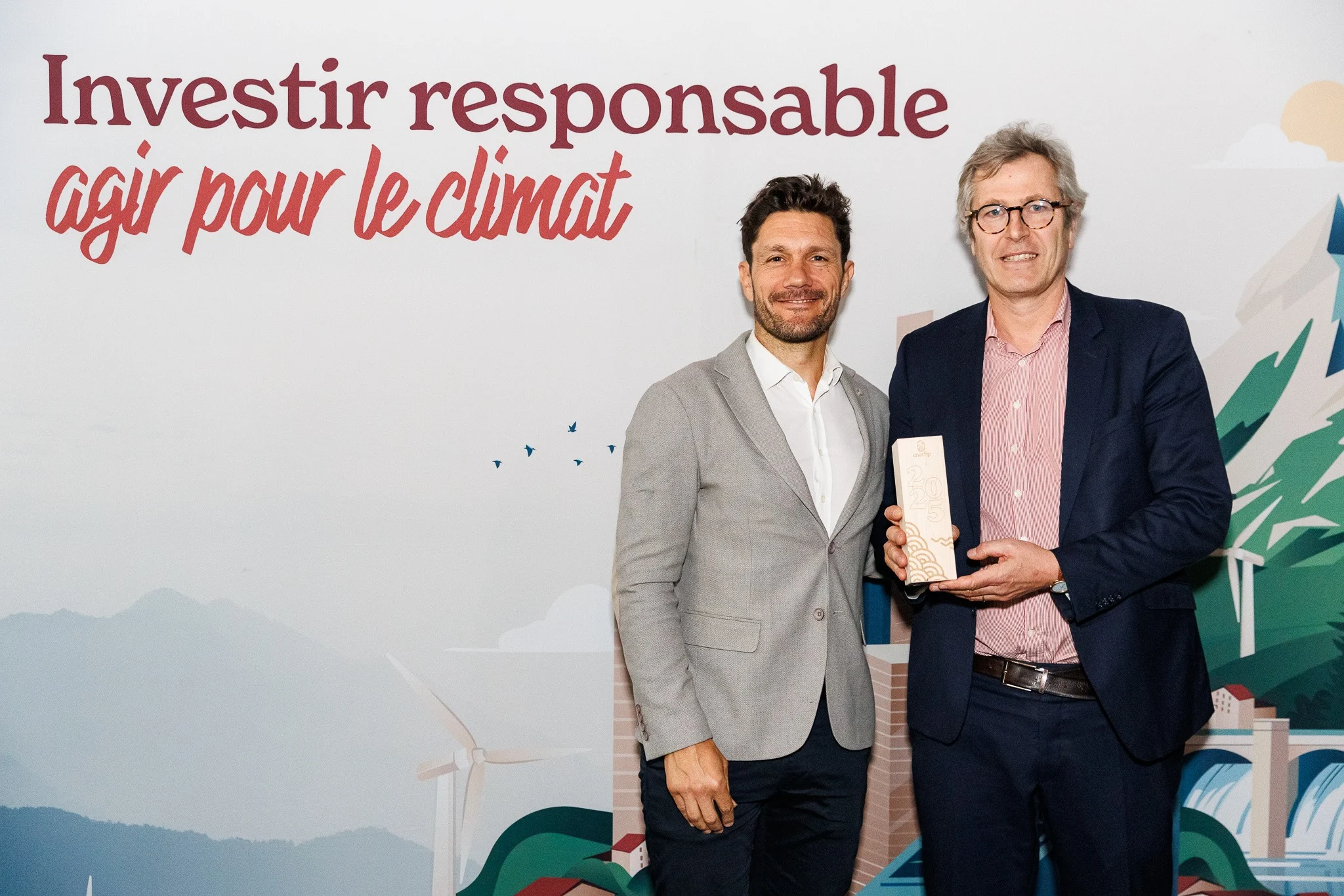 Deux hommes posent devant un fond sur lequel on peut lire « Investir responsable, agir pour le climat », l'homme de droite tenant un trophée portant l'inscription « 2025 ».