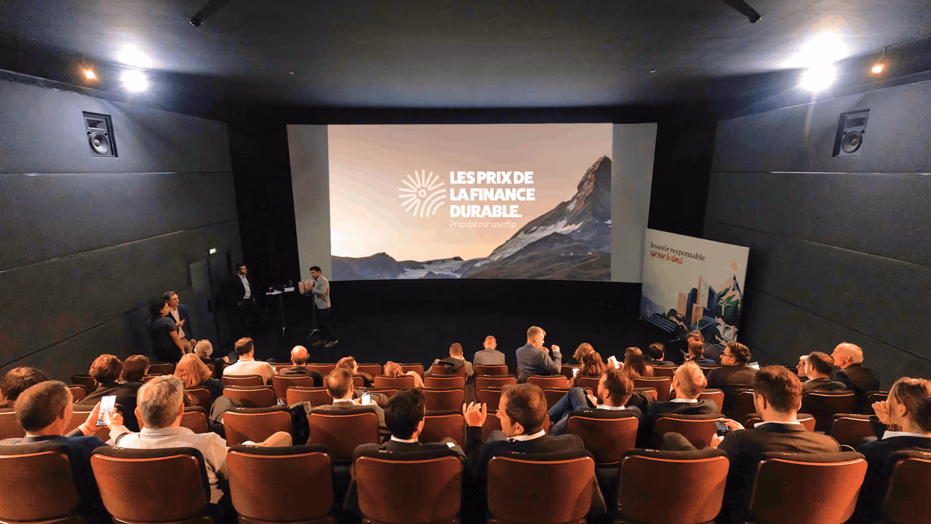Des personnes assises dans une salle de cinéma en train de regarder une présentation sur le financement durable.