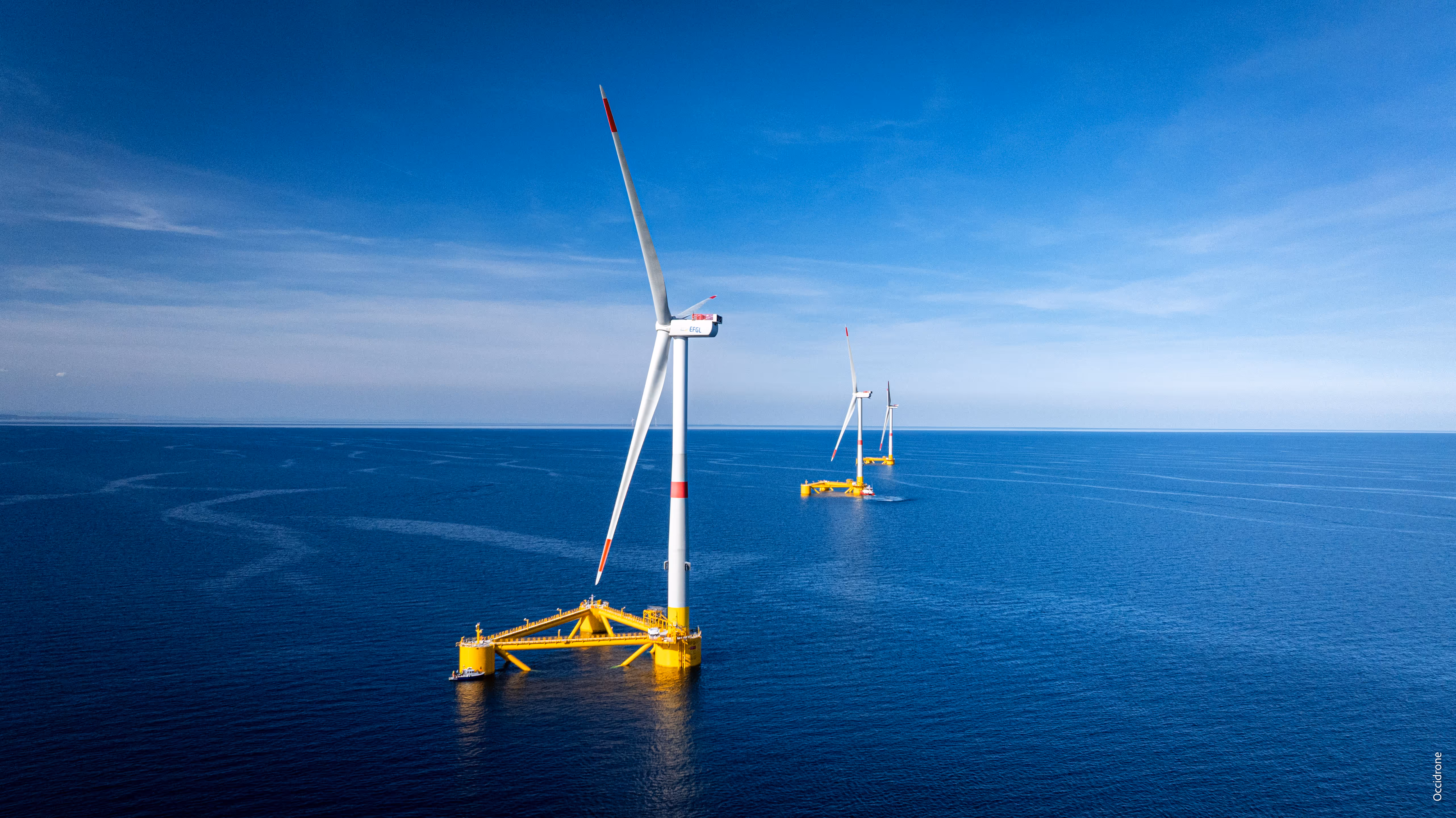 Des éoliennes flottantes en mer sous un ciel bleu par temps ensoleillé.