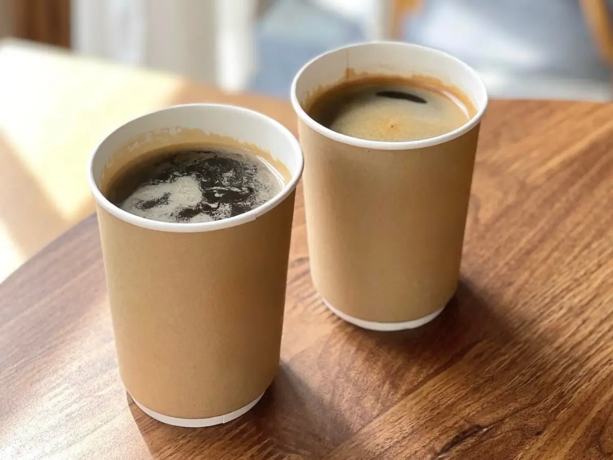 Woman passing coffee cups with holder to another woman