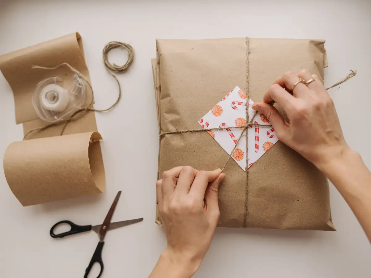 Hands wrap a brown paper package with twine 