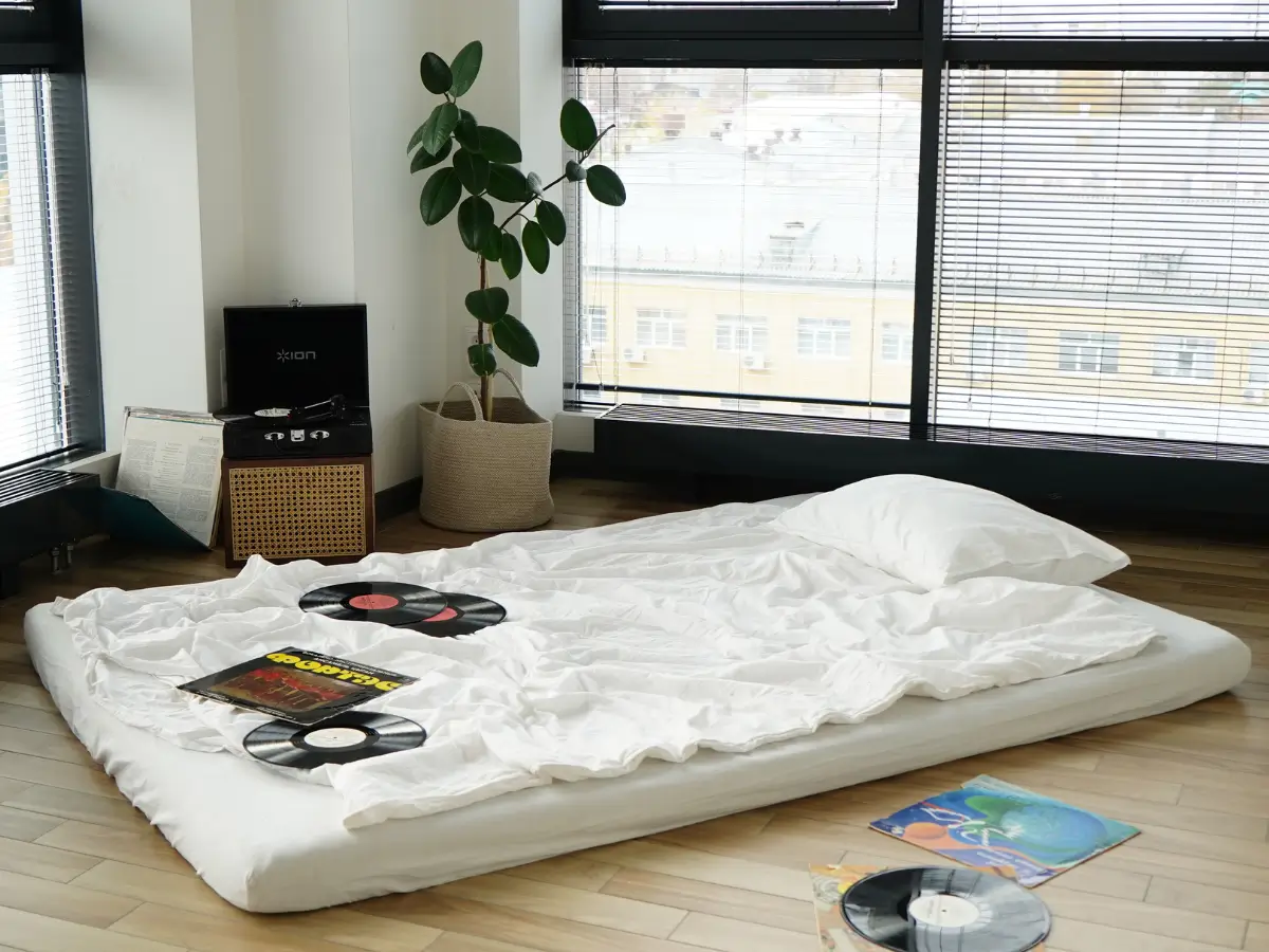 A mattress lies on the floor with records