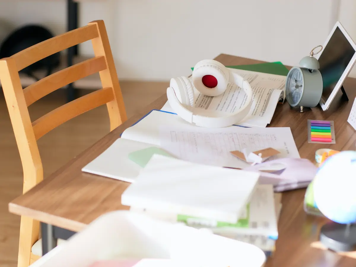 A chair sits it front of a desk cluttered with paper, office supplies, and post-its