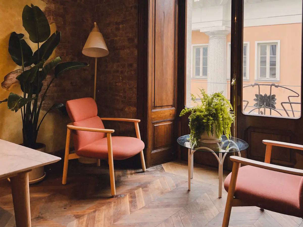 Older furniture sits in a wooden room with a plant and a view out the window