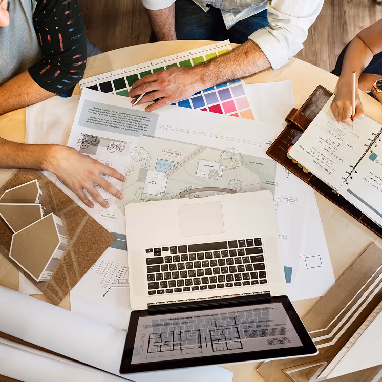 Designers seated at a table, working on construction documentation and consulting with a client.