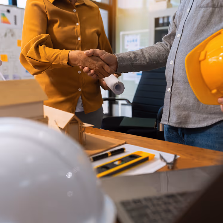 Contractor and client shaking hands, finalizing an agreement or celebrating project progress.