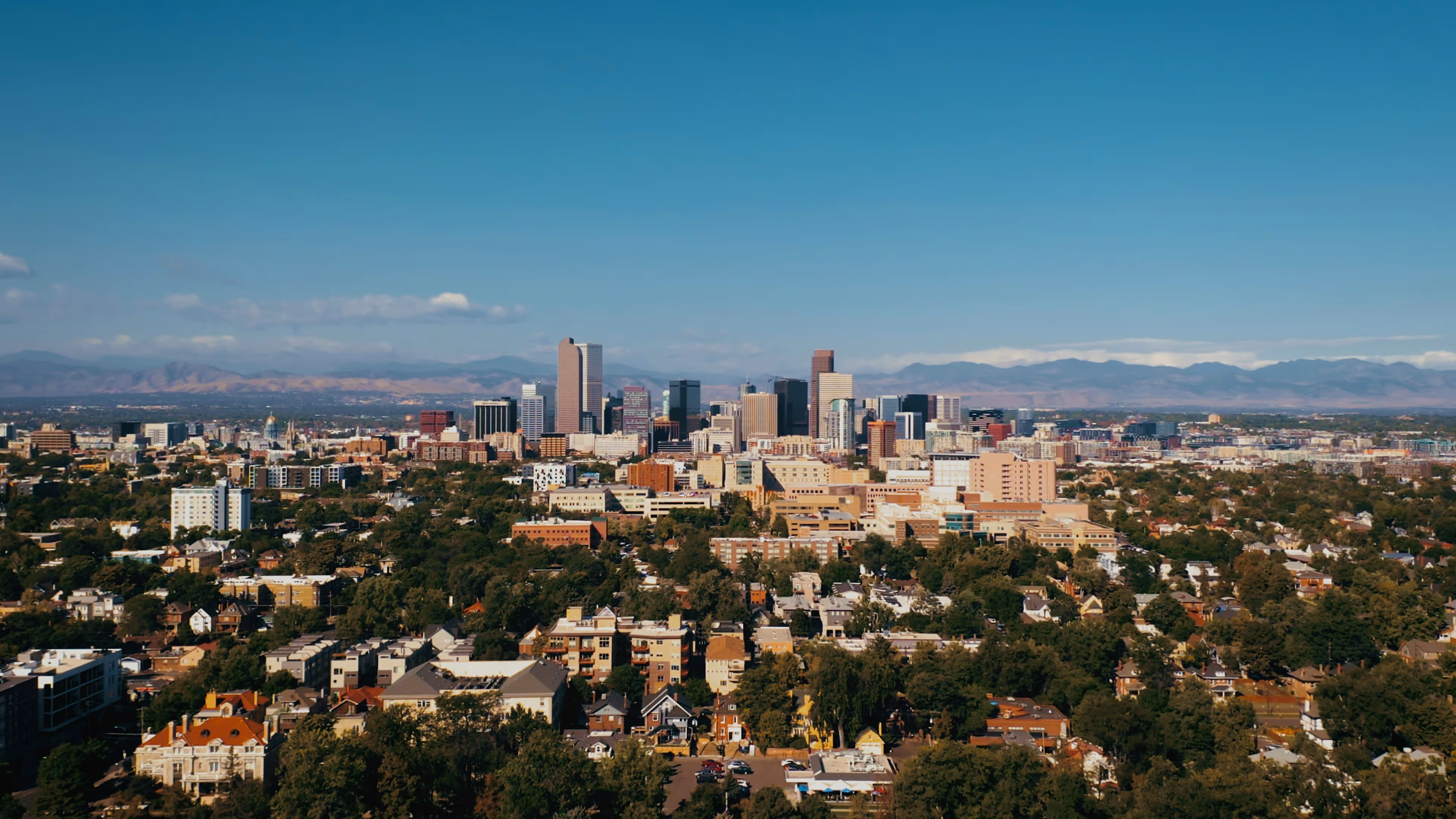 View of the Denver skyline with city buildings and mountain backdrop.