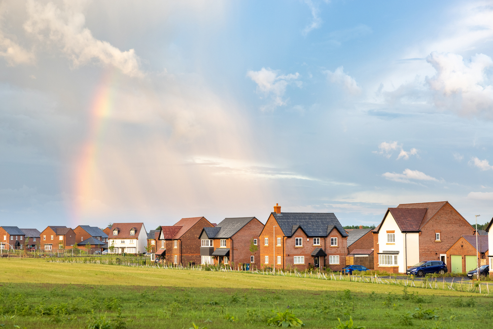 Wide view of housing, featuring green grass and blue skies