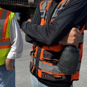 A construction worker holds a palm cooling device called the Narwhals for heat stress mitigation. 