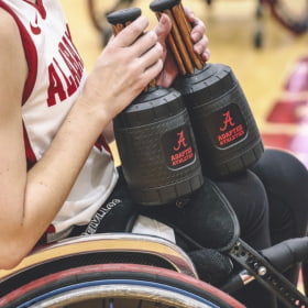 A wheelchair basketball player holds a palm cooling device during a game