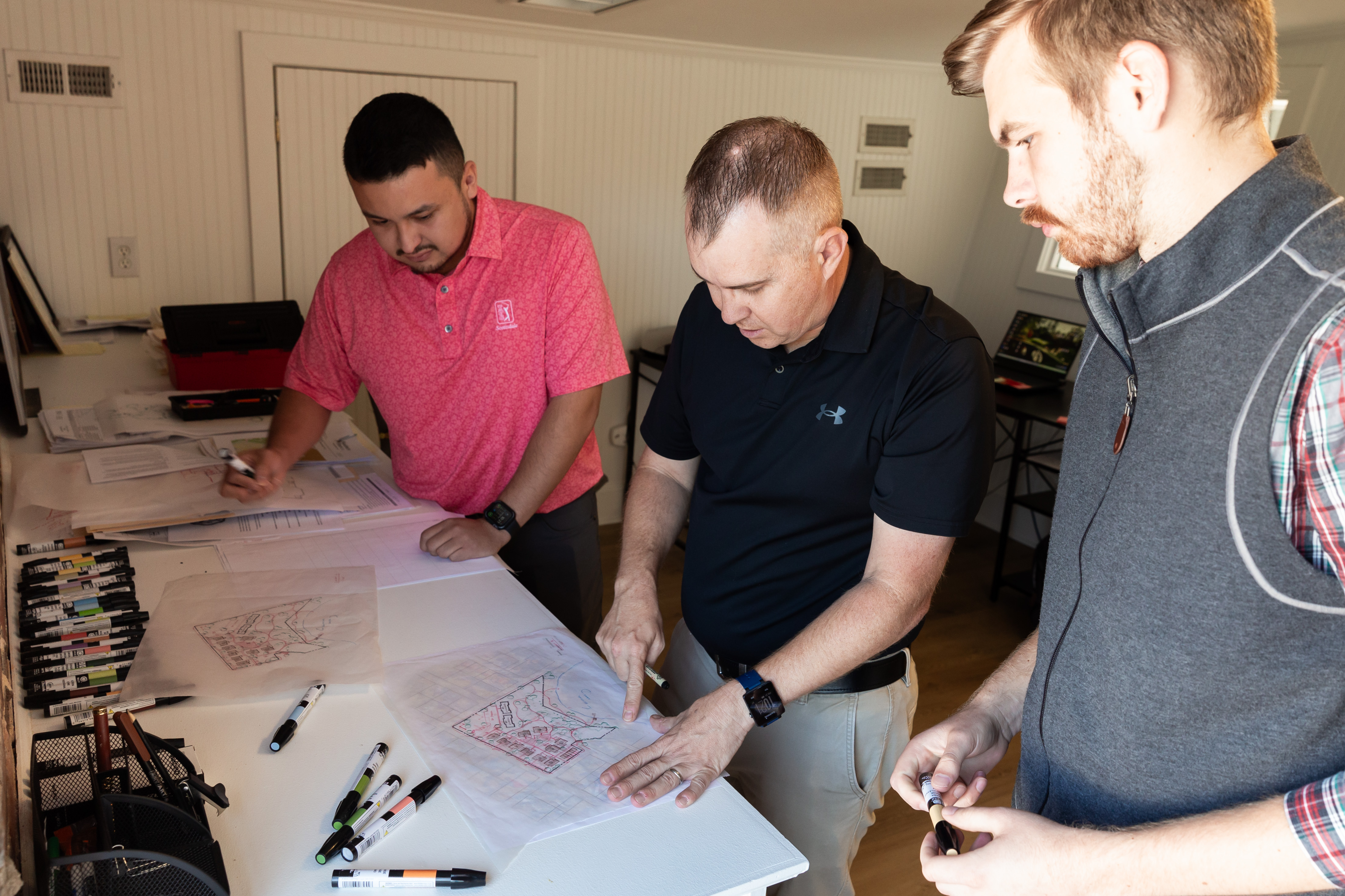The Longitude Planning Team pictured huddled around a few design drawings
