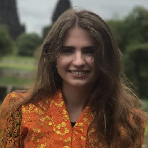 Smiling person in bright orange floral top standing outdoors