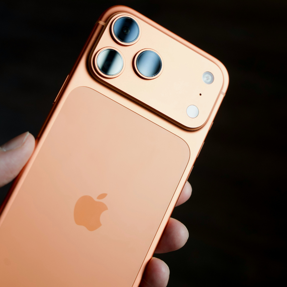 A hand holding an iphone 17 pro max orange