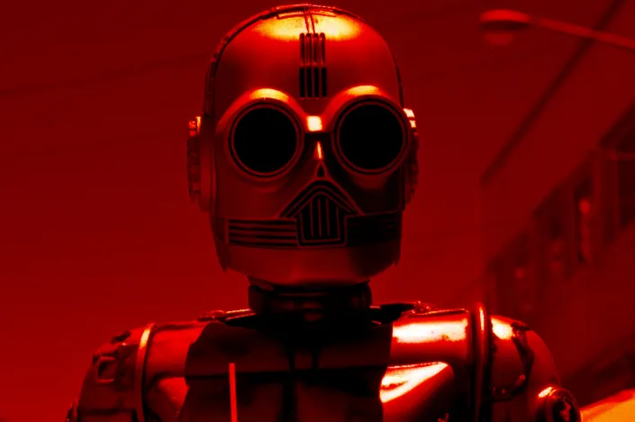 A grinning robot who is representative of investigation (inquiry) and working to an ideology