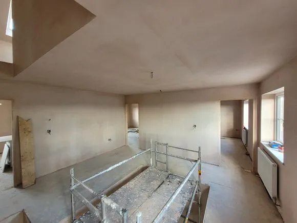 A freshly plastered room with a metal scaffolding in it.