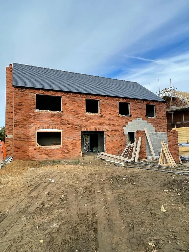A brick house with a slanted roof with open holes ready for windows.