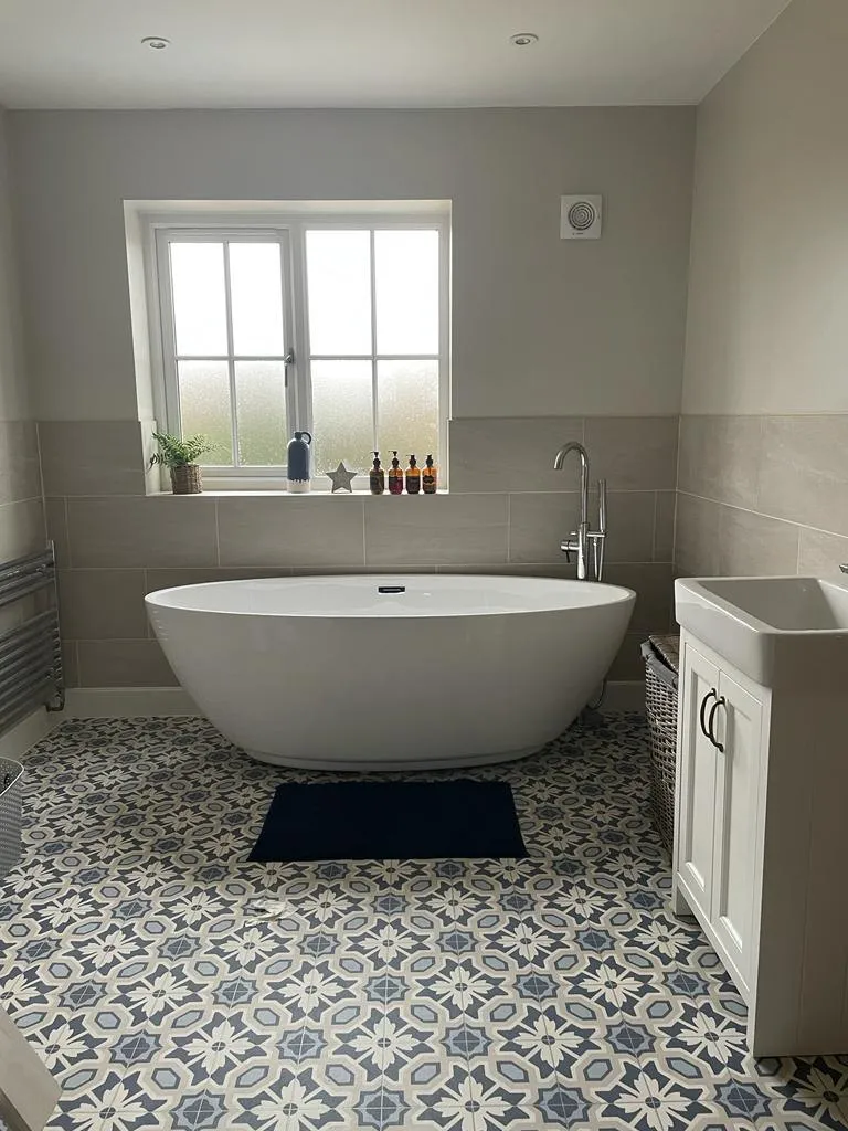 A bathroom with a white bathtub and a blue rug.