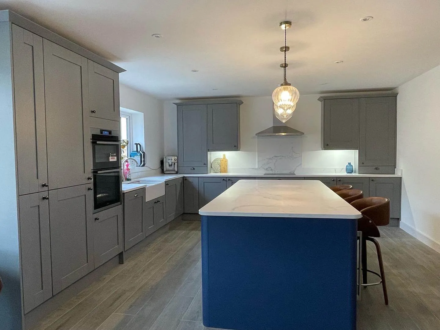 A large kitchen with a blue island and a hanging light.