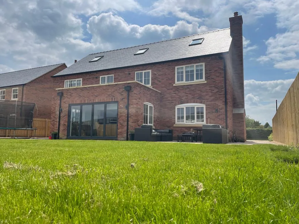 The rear large brick house with an extension and black patio set.