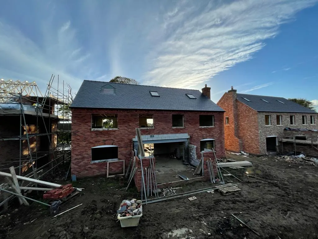 A large brick house under construction, nearing completion.