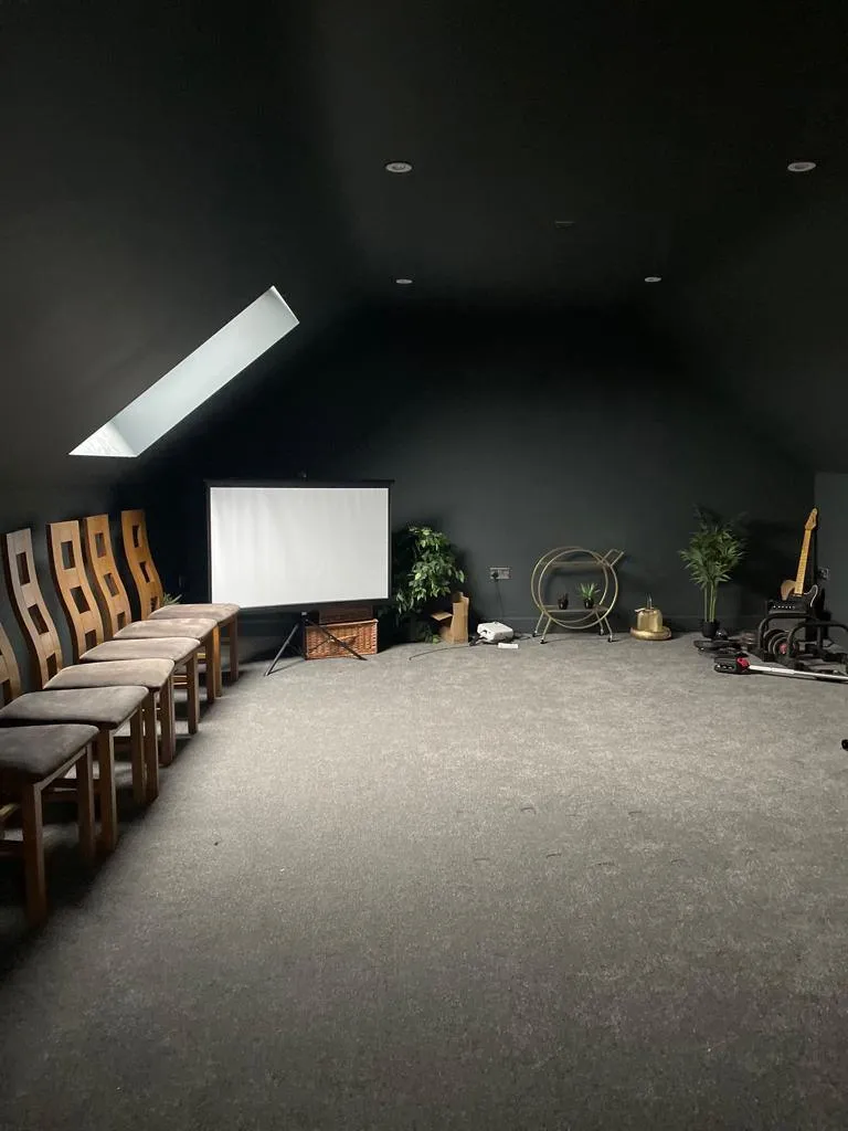 A dark room with a projector screen and a large window.