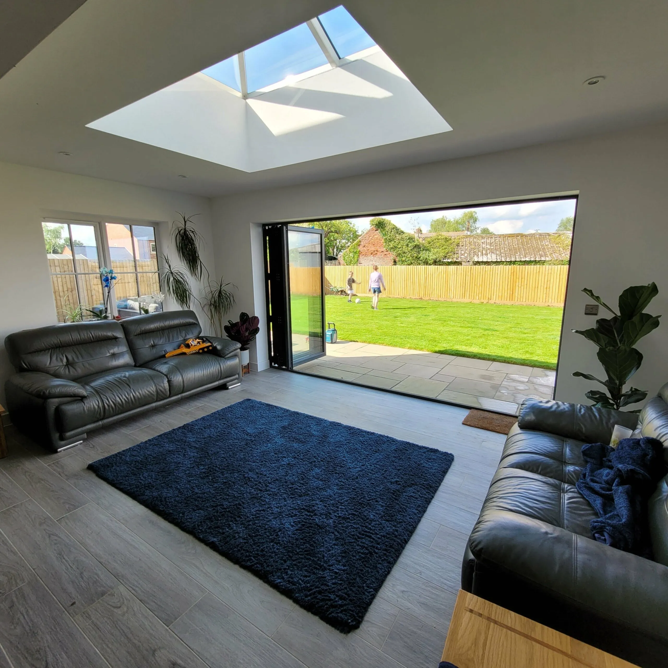 A living room with a black couch and a blue rug.