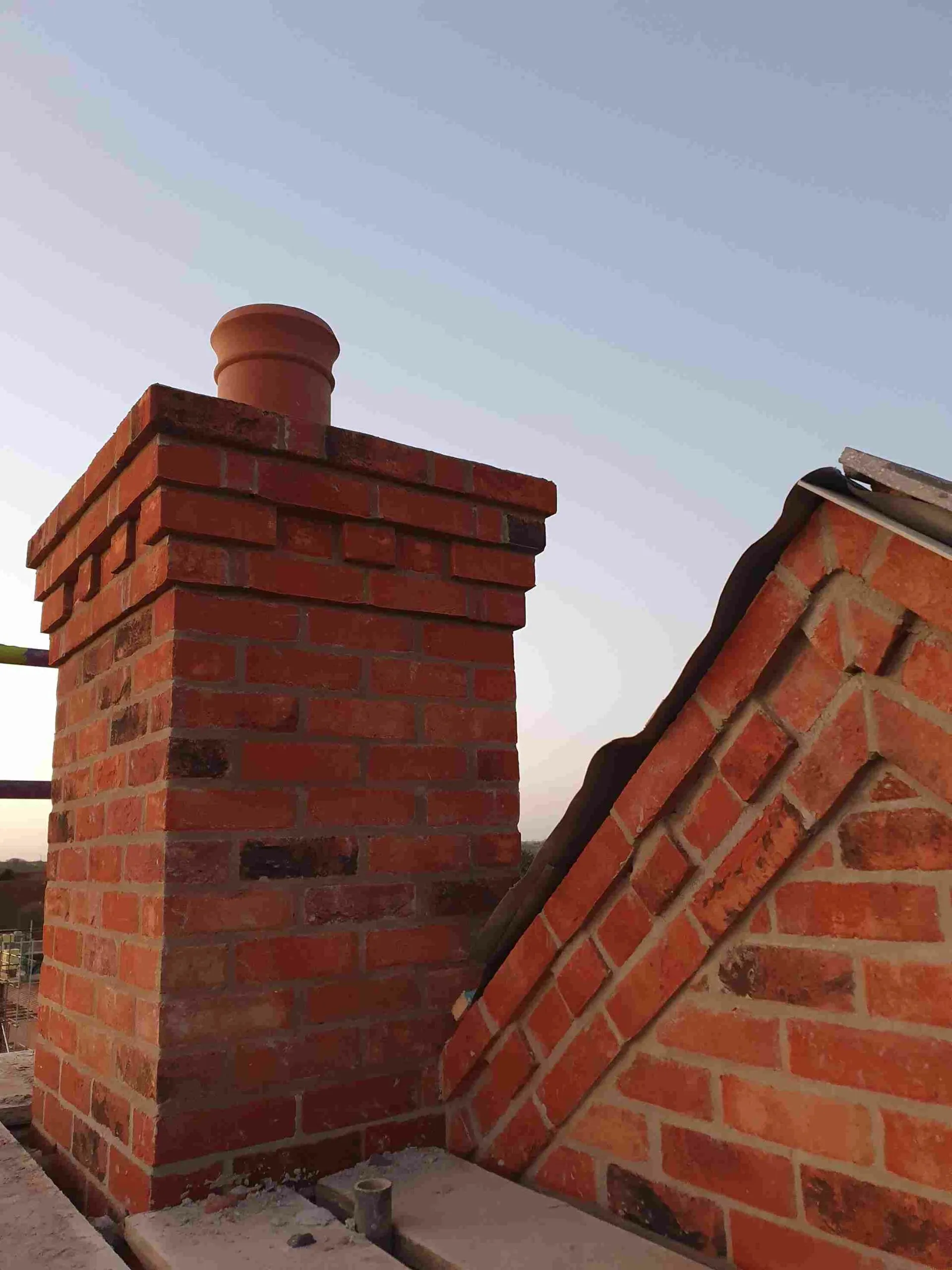 A brick chimney with a red brick roof.