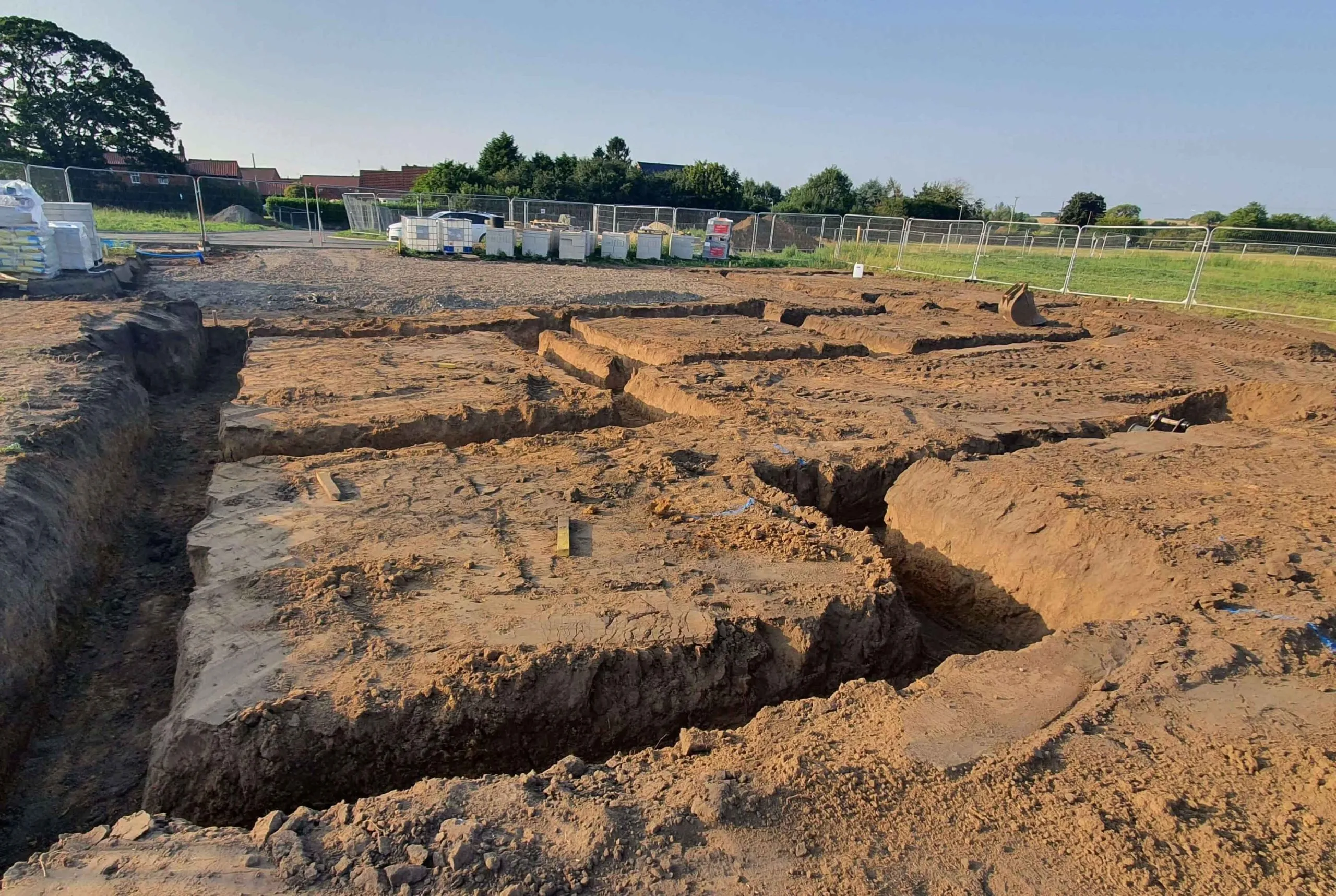 A large dirt hole in the ground, ready for foundations.