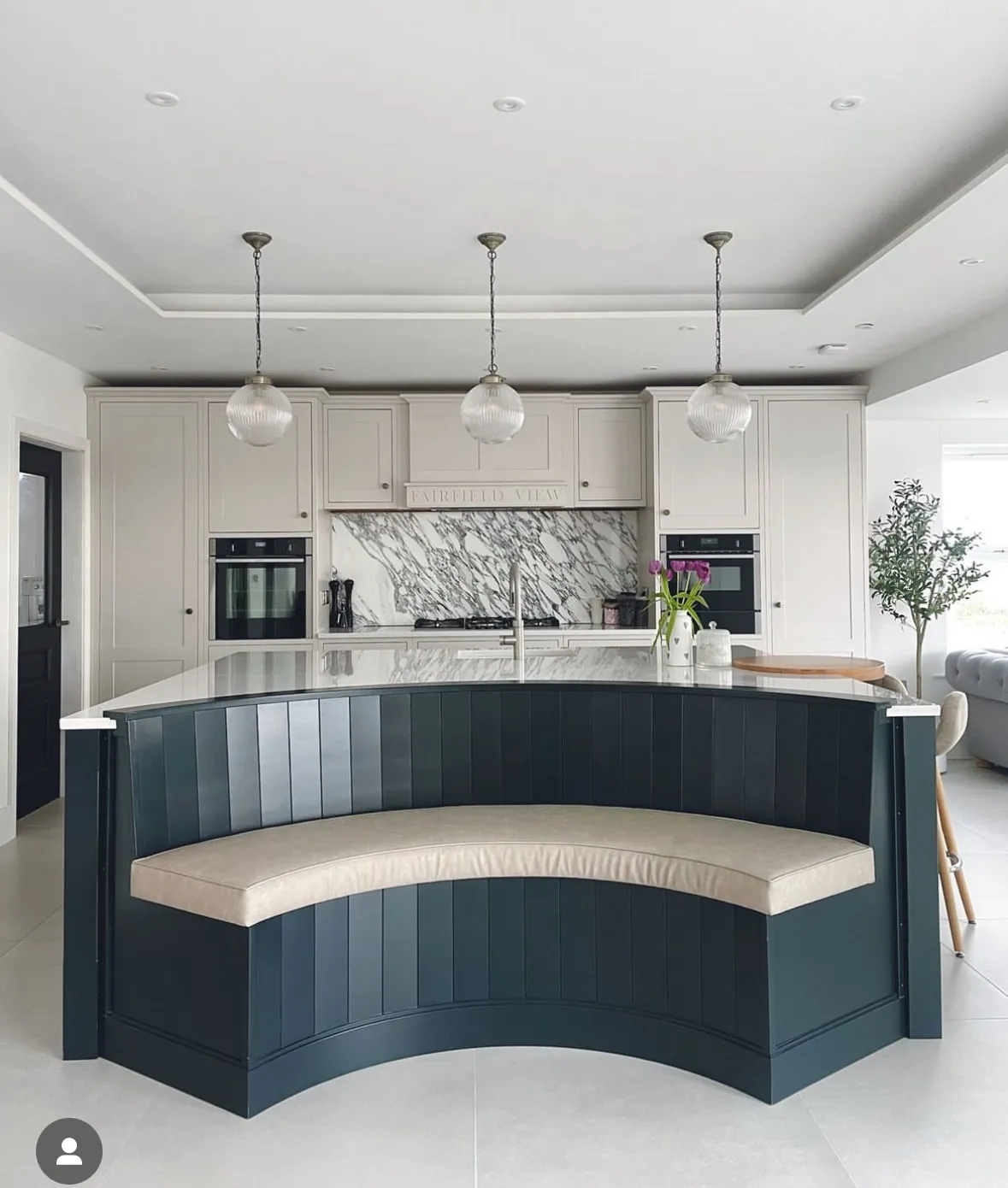 A kitchen with a black island and white cabinets.