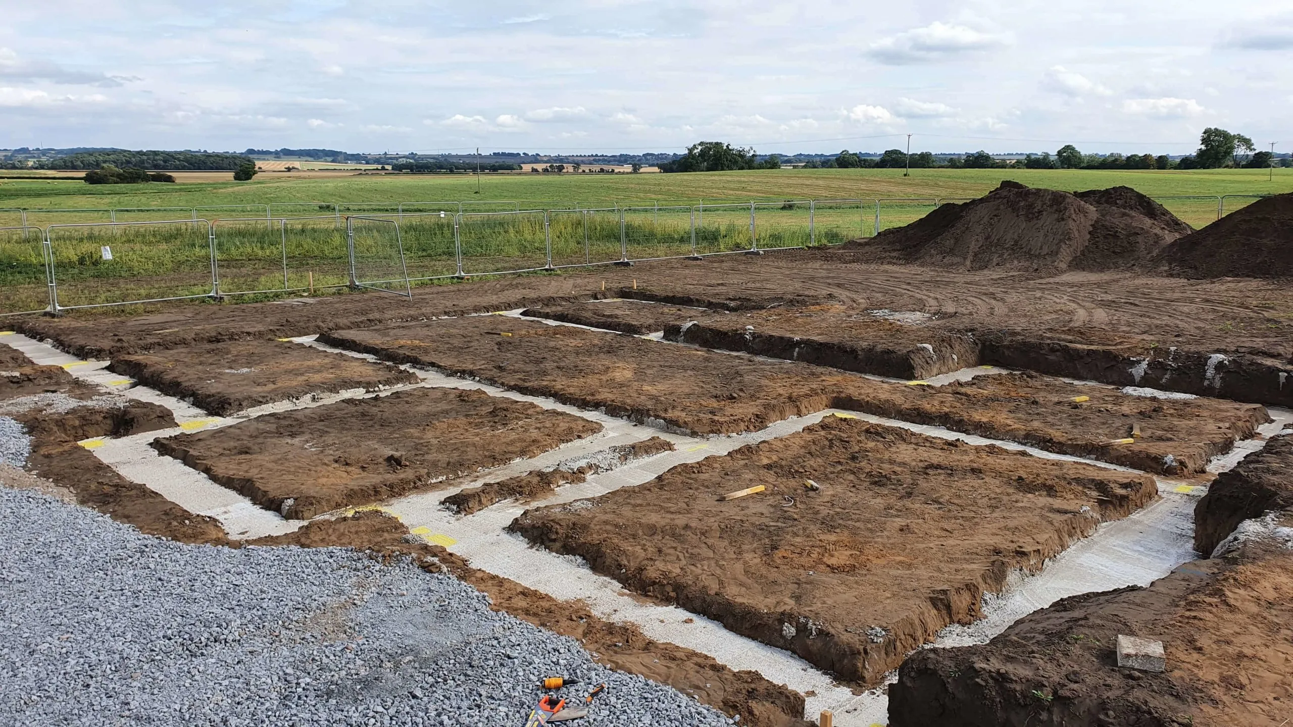 A large dirt hole in the ground, ready for foundations.