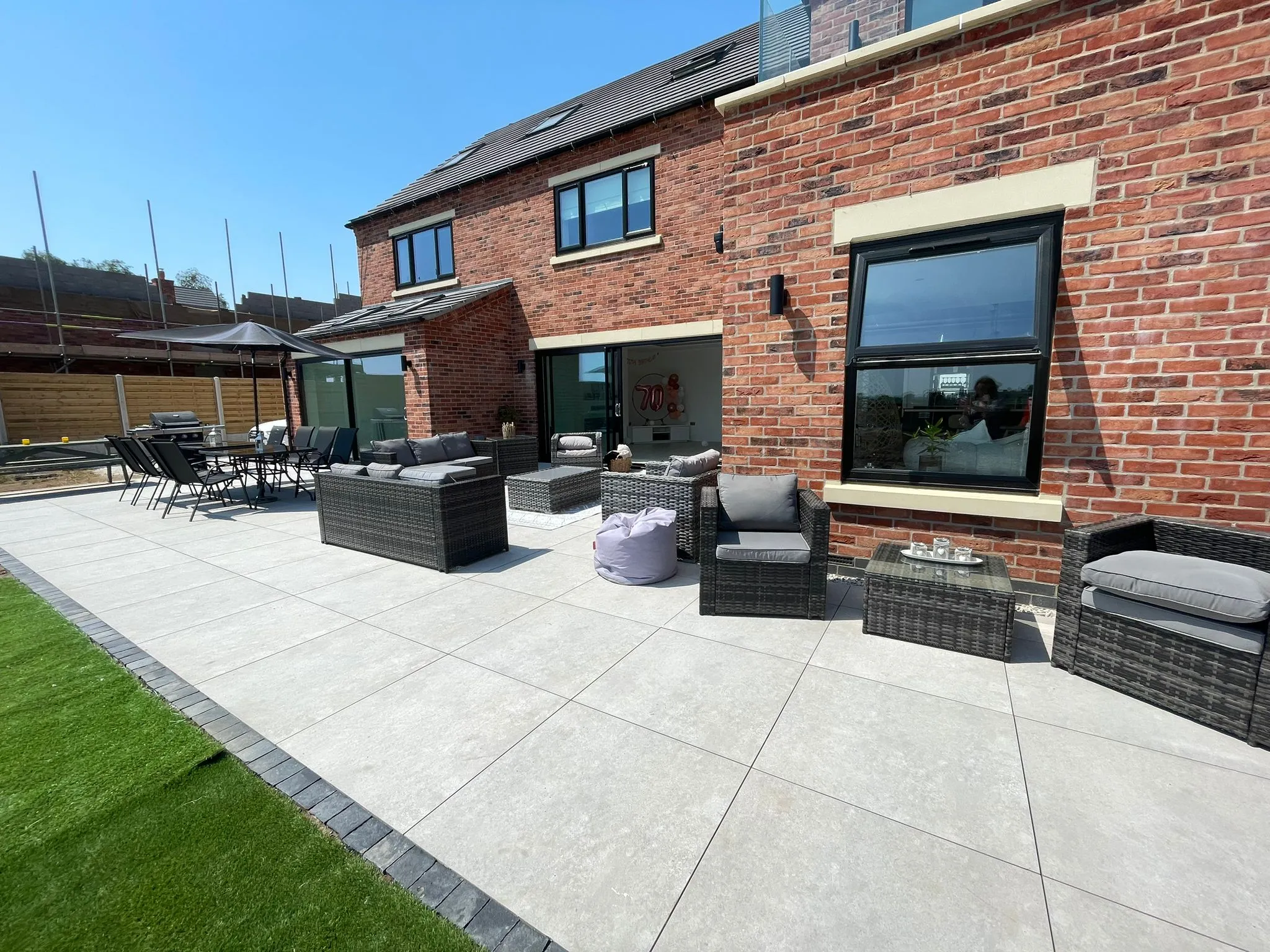 A large brick house with a patio and garden furniture.