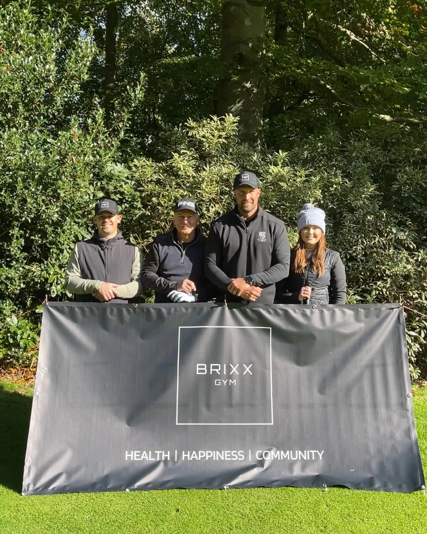A group of people standing in front of a sign that says Brixx Gym.