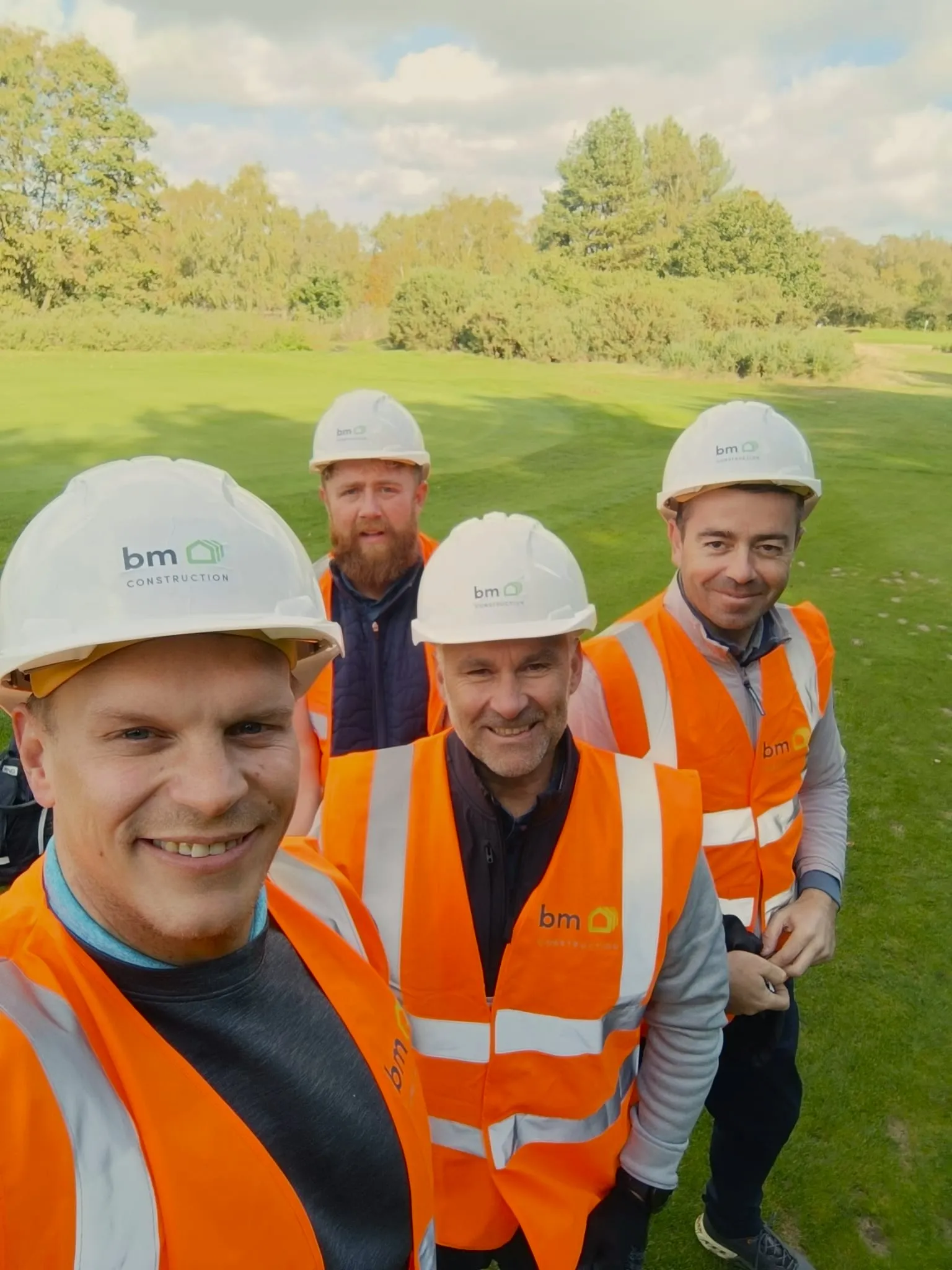 A group of construction workers wearing hard hats and orange vests.