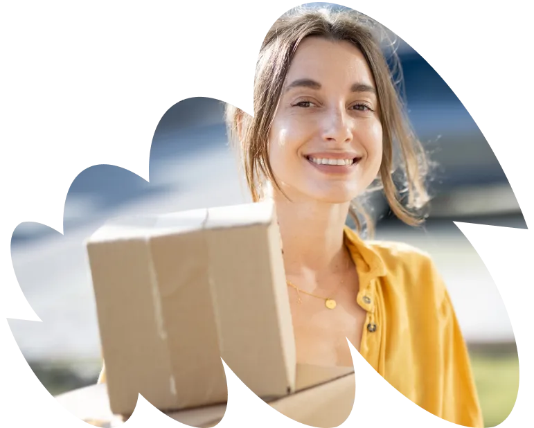 A woman holding a cardboard box and smiling.