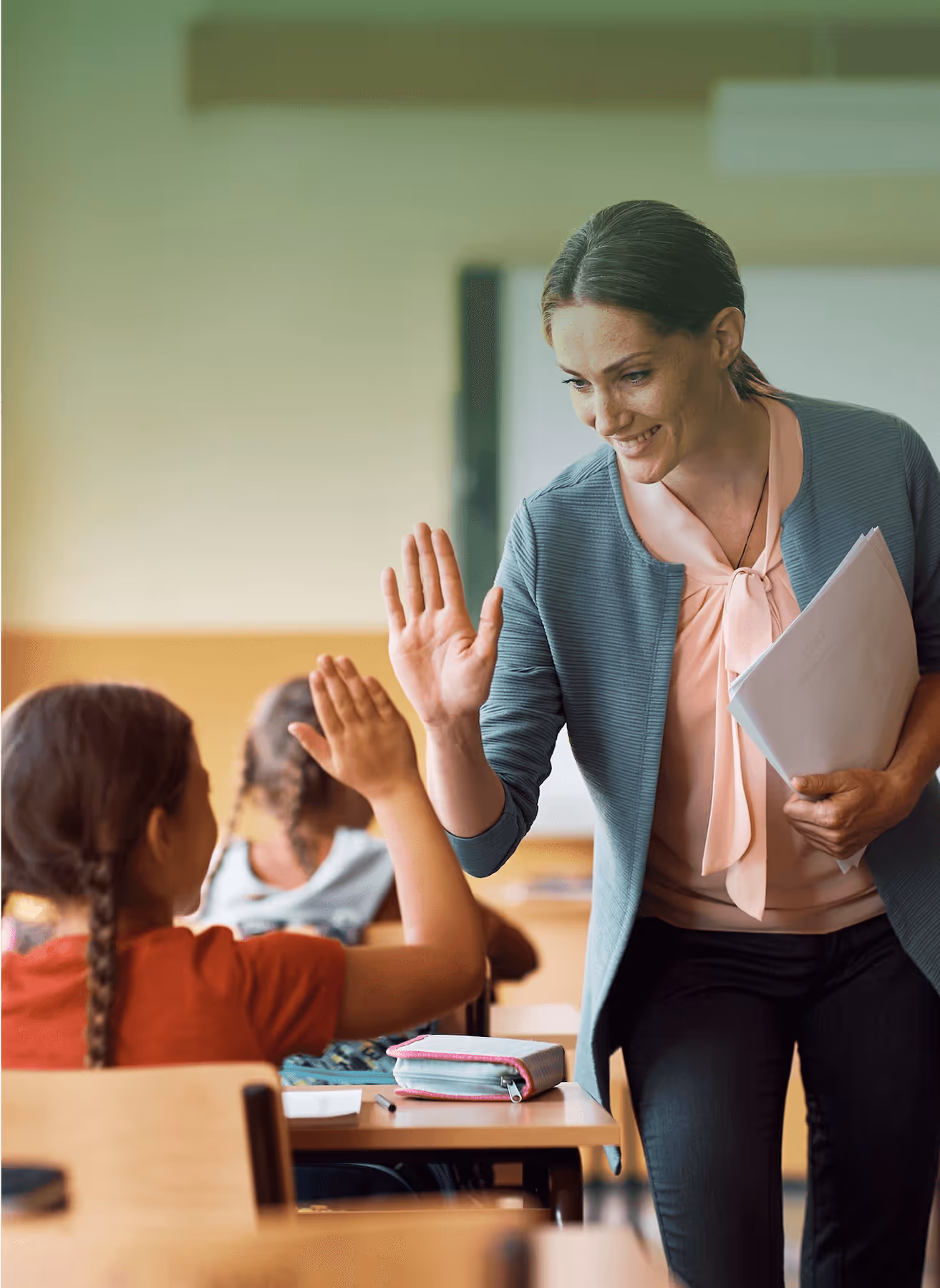 A teacher enthusiastically gives high fives to smiling students in a vibrant classroom setting.