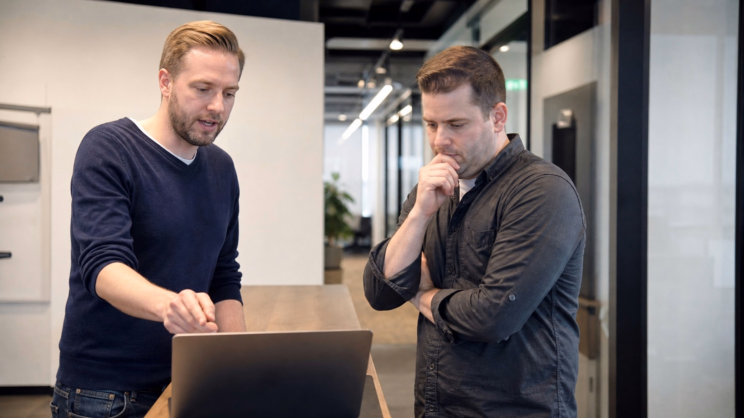 INFORMAL HUDDLE An IT professional  two people standing and talking near a ki
