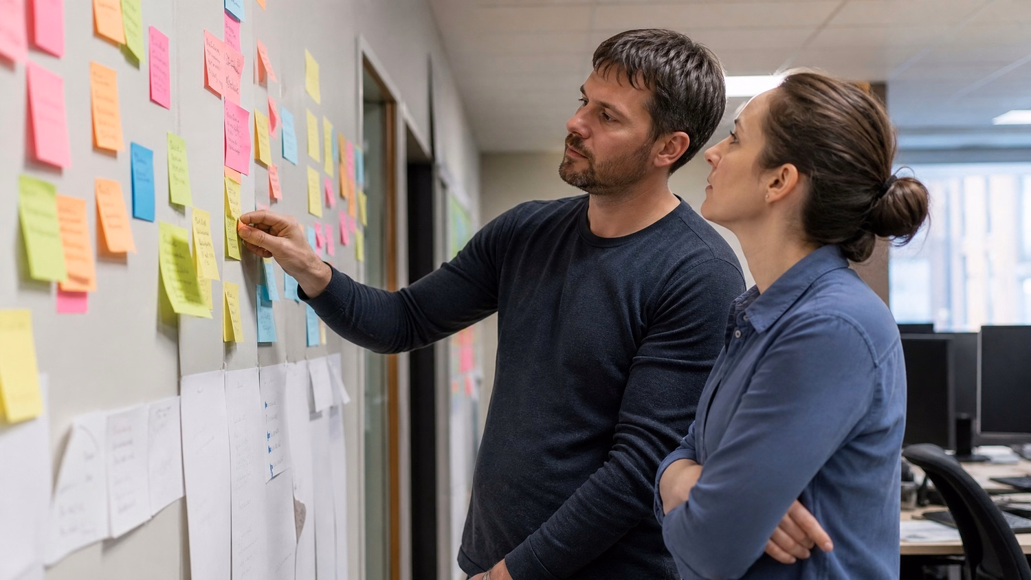 STICKY NOTE WALL An IT professional  two people standing at a wall covered wi
