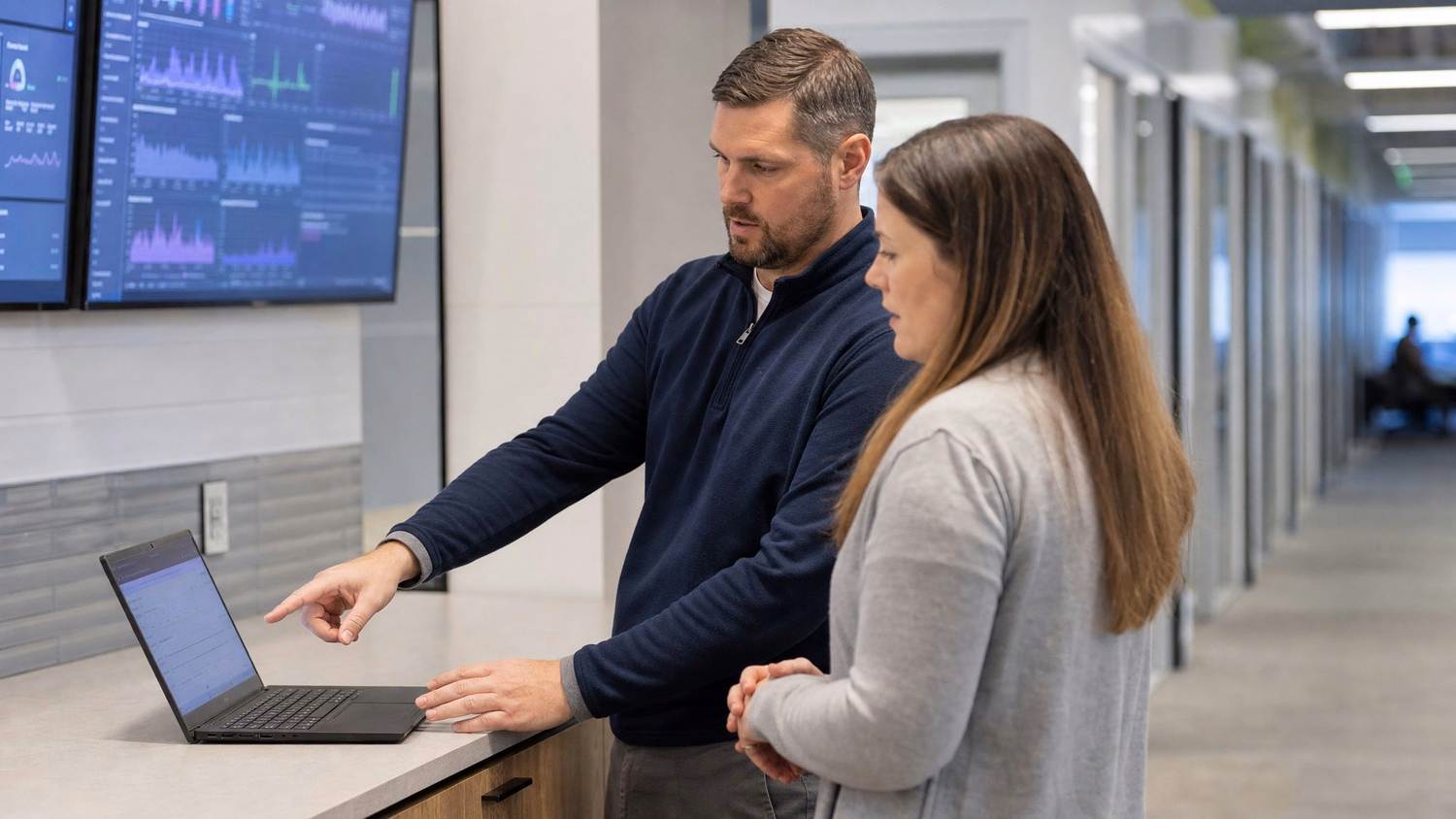 INFORMAL HUDDLE An IT professional two people standing and talking near a ki