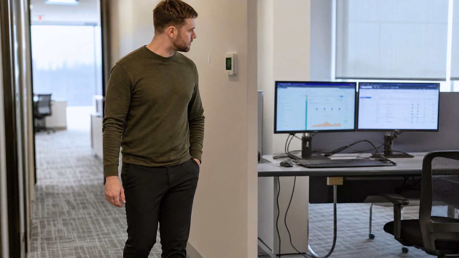 Architect walks past dual monitors, loose cable visible