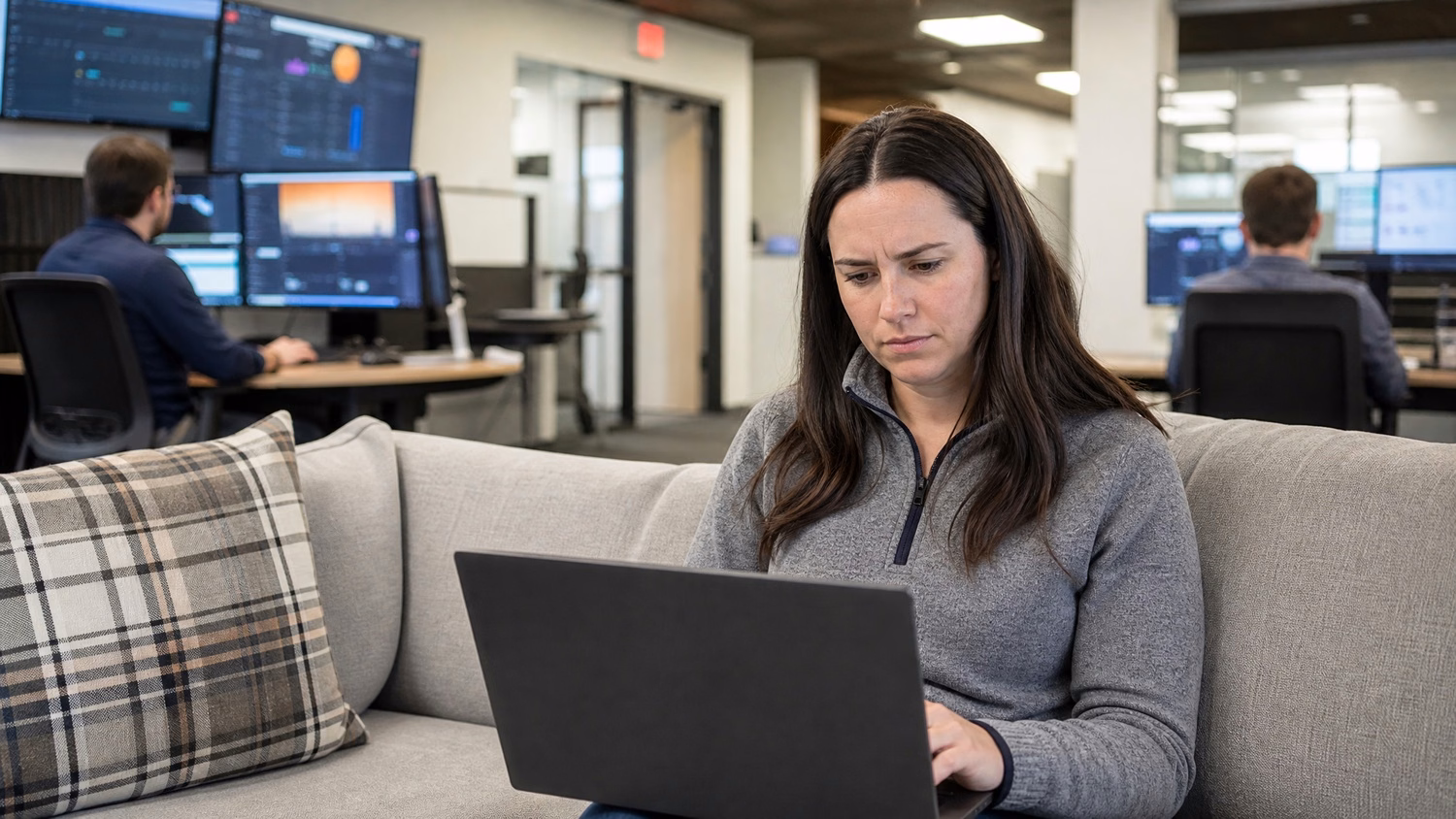 Woman analyzes security alerts on laptop in office lounge