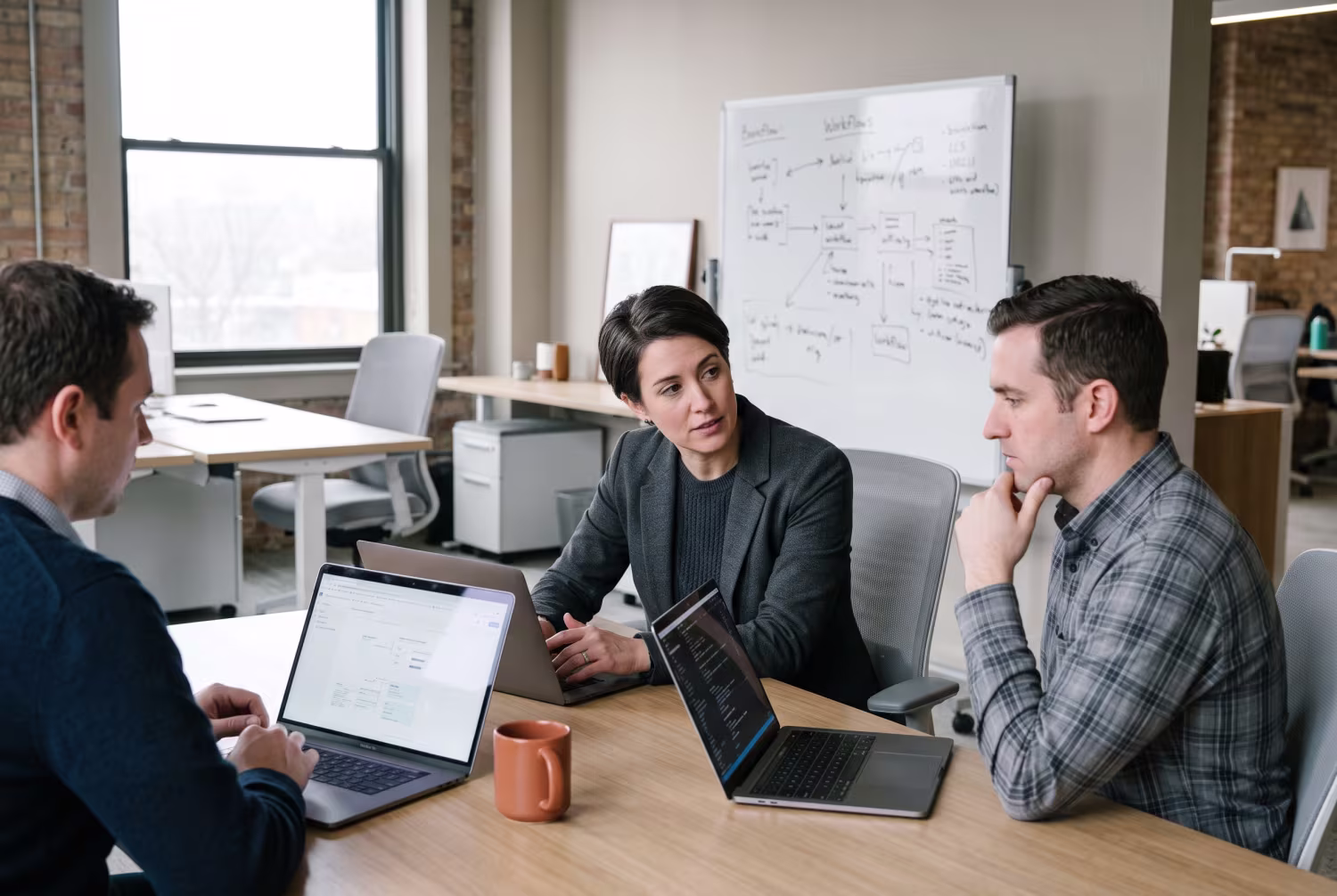 Three IT professionals discussing AI solutions around laptops