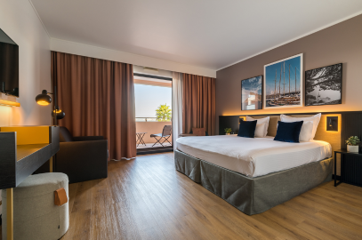 Chambre Deluxe de la Villa M à Marseille avec grand lit double, parquet, coin bureau design, balcon aménagé, dans une ambiance chaleureuse aux tons bruns et dorés.