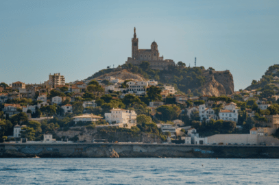 Vue depuis la mer Méditerranée sur la ville de Marseille, s'étendant sur les collines verdoyantes jusqu'à la basilique Notre-Dame de la Garde située au sommet.